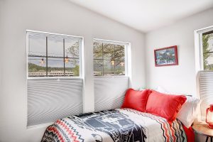 Bedroom in the Grand Canyon Train house in Williams, Arizona with a patterned bedset, industrial decor, and a view of the Grand Canyon Railway through the windows
