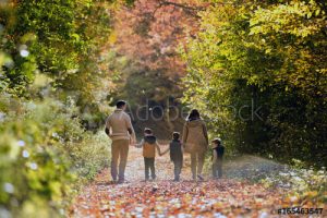 photo of a family of 5 walking through the woods in Autumn