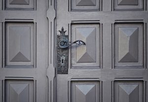 image is of a gray door with a gothic style door handle